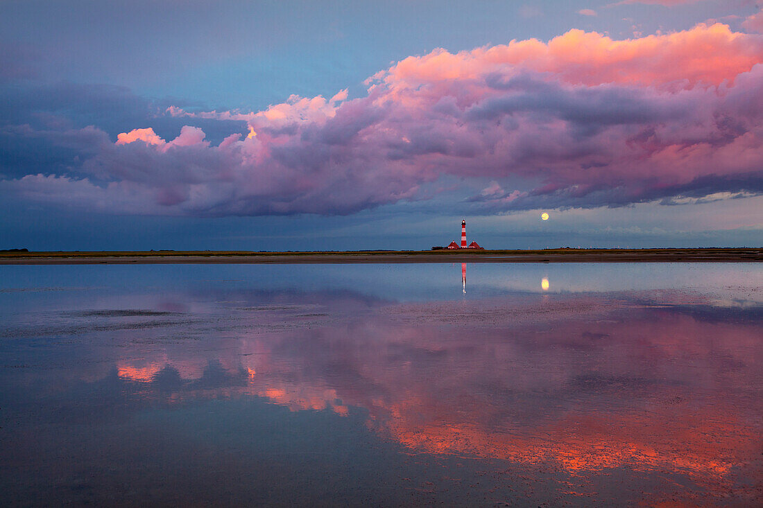 Lighthouse, clouds and moon reflecting in the flats near Westerhever lighthouse, Eiderstedt peninsula, Schleswig-Holstein, Germany