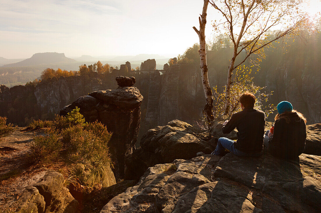 Young couple resting at a lookout point, view over Wehlgrund to Bastei rocks, Lilienstein in the background, National Park Saxon Switzerland, Elbe Sandstone Mountains, Saxony, Germany