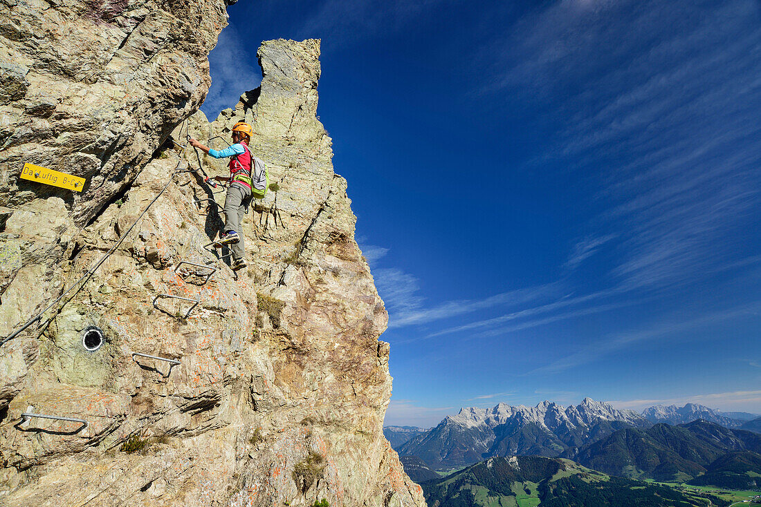 Woman ascending fixed rope route, Loferer Steinberge range in background, fixed rope route Henne, Henne, Kitzbuehel range, Tyrol, Austria