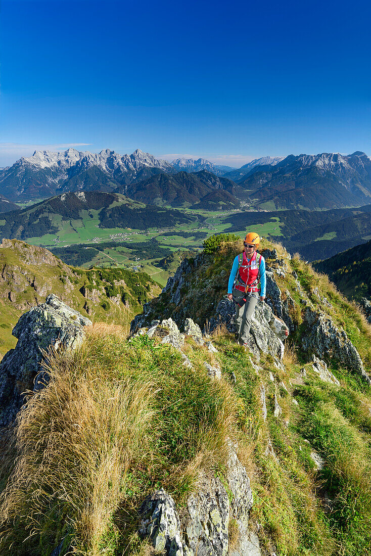 Frau steigt über Bergrücken auf, Loferer Steinberge im Hintergrund, Klettersteig Henne, Henne, Kitzbüheler Alpen, Tirol, Österreich