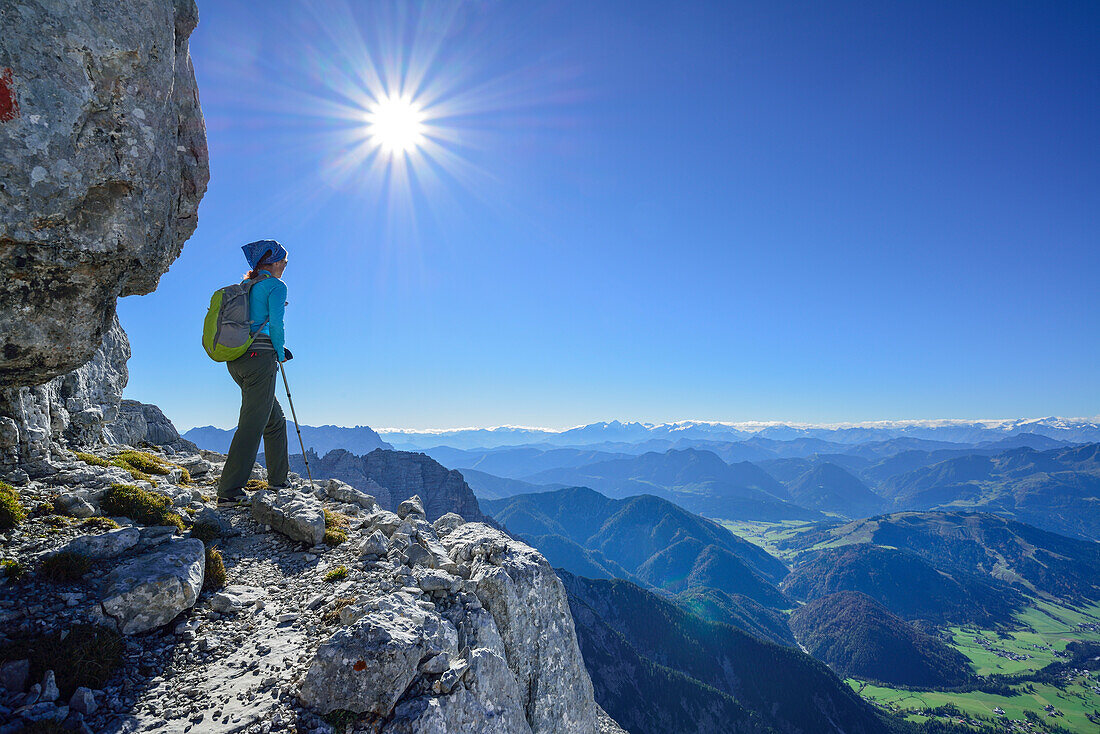 Woman hiking on rocky ledge with view to Hohe Tauern range, Nurracher Hoehenweg, Loferer Steinberge range, Tyrol, Austria