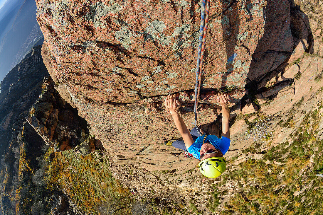 Woman climbing on red Granite rock, Mottarone, Piedmont, Italy