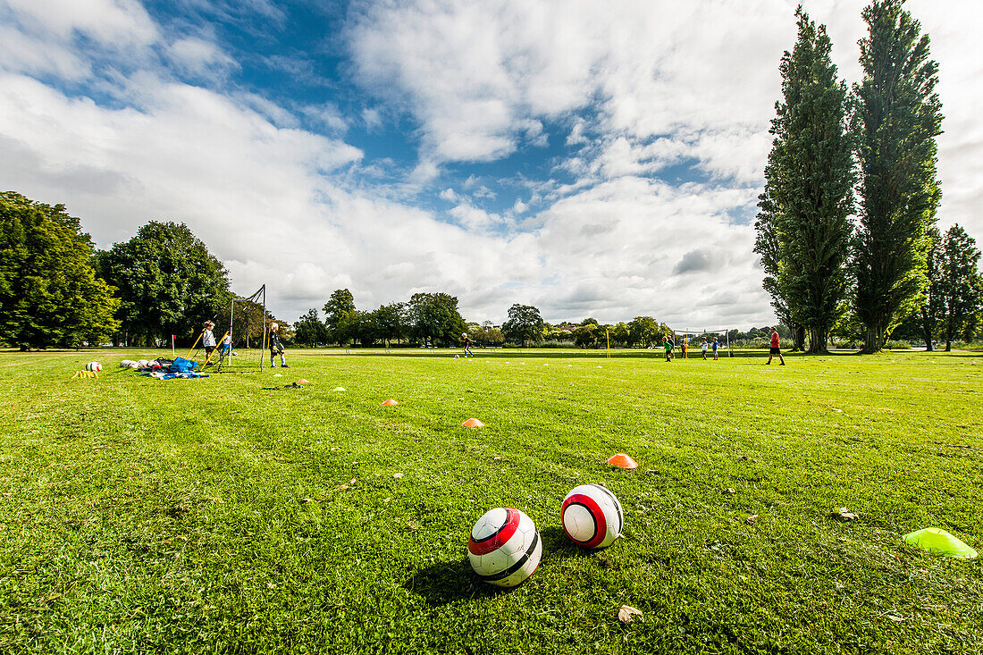 Two balls in grass, soccer players in background, Hamburg, Germany