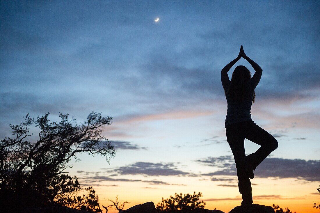 Frau in Yoga-Pose bei Sonnenuntergang am Grand Canyon.