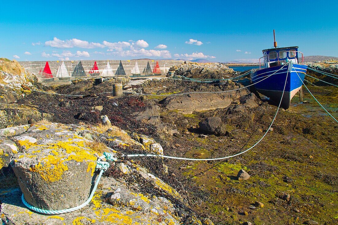 Small fishing boat resting on its keel at low tide on Lettermore Island, County Galway, Ireland.