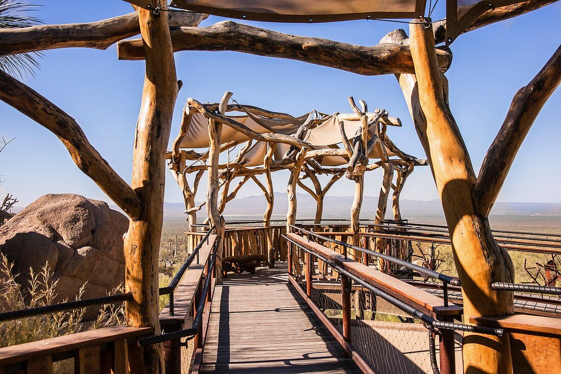 Mesquite wood and a canopy form a shaded ramada overlooking the vast southwestern desert.