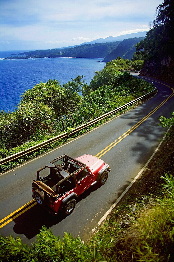 Roter Jeep auf einer Küstenstraße auf Hawaii