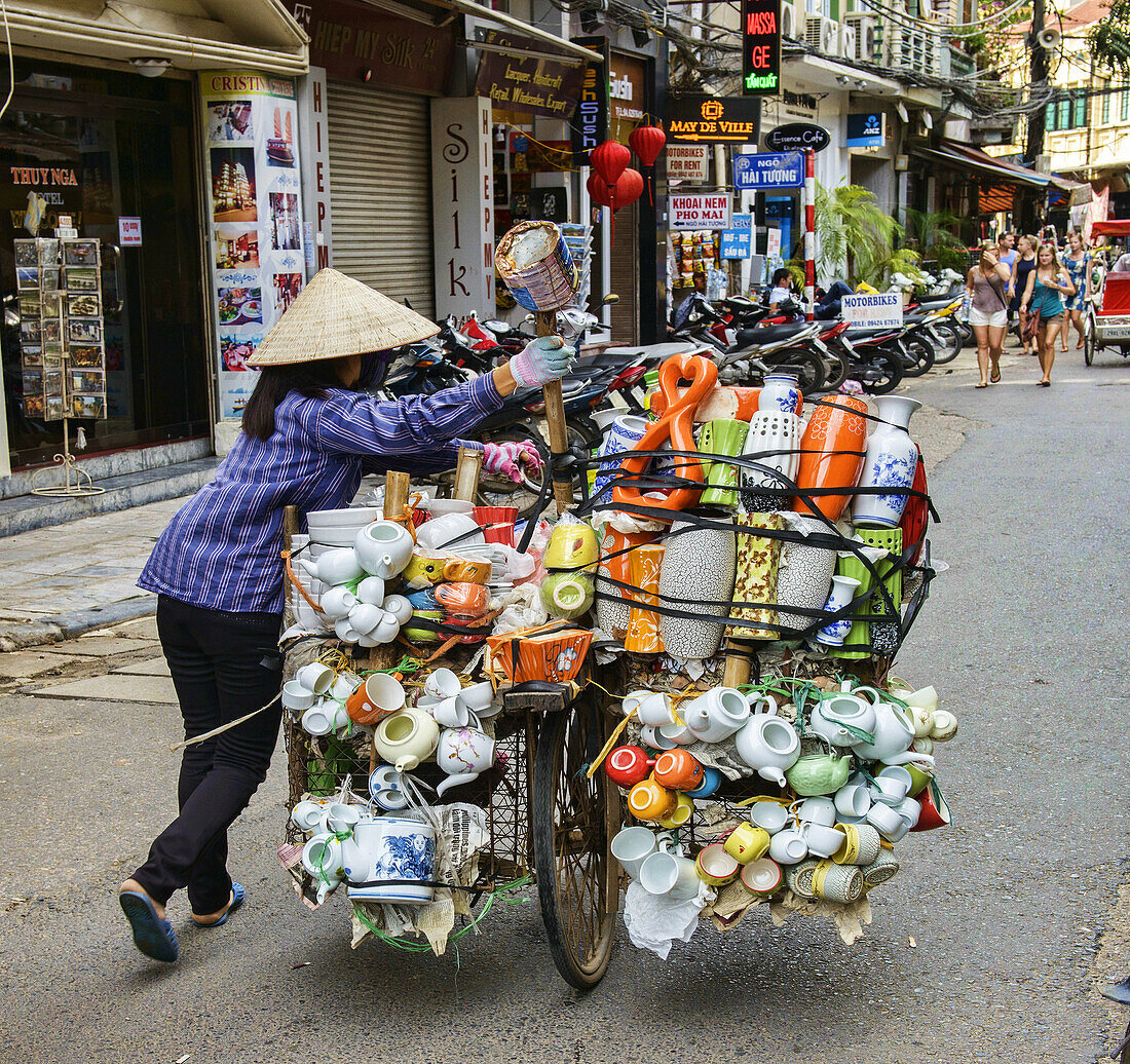 vendor pushes her load through the streets in Hanoi, Vietnam.