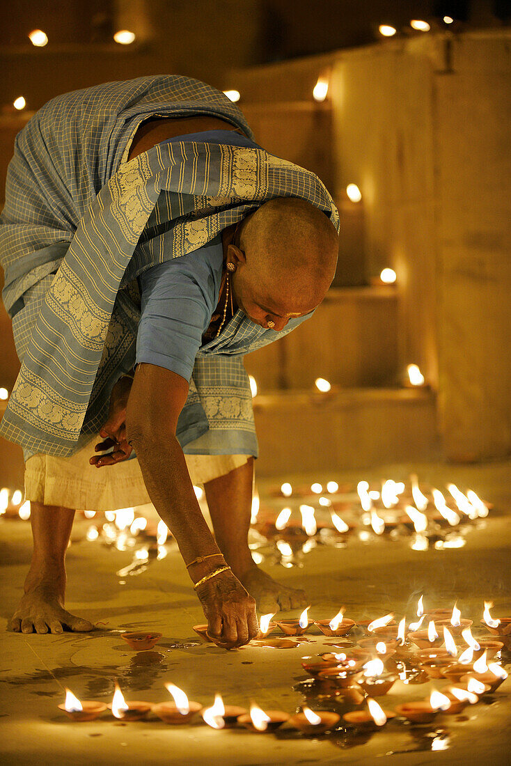 India, Uttar Pradesh, Varanasi, Dev Deepawali festival, Hindu devotee lighting oil lamps.