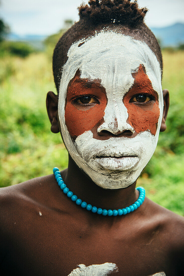 'Surma child with face painted with pigment made from powdered coloured stones, Omo region, Southwest Ethiopia; Kibish, Ethiopia'