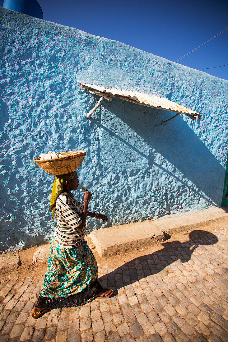 'A young girl walking through the colourful streets of the old city of Harar in Eastern Ethiopia; Harar, Ethiopia'