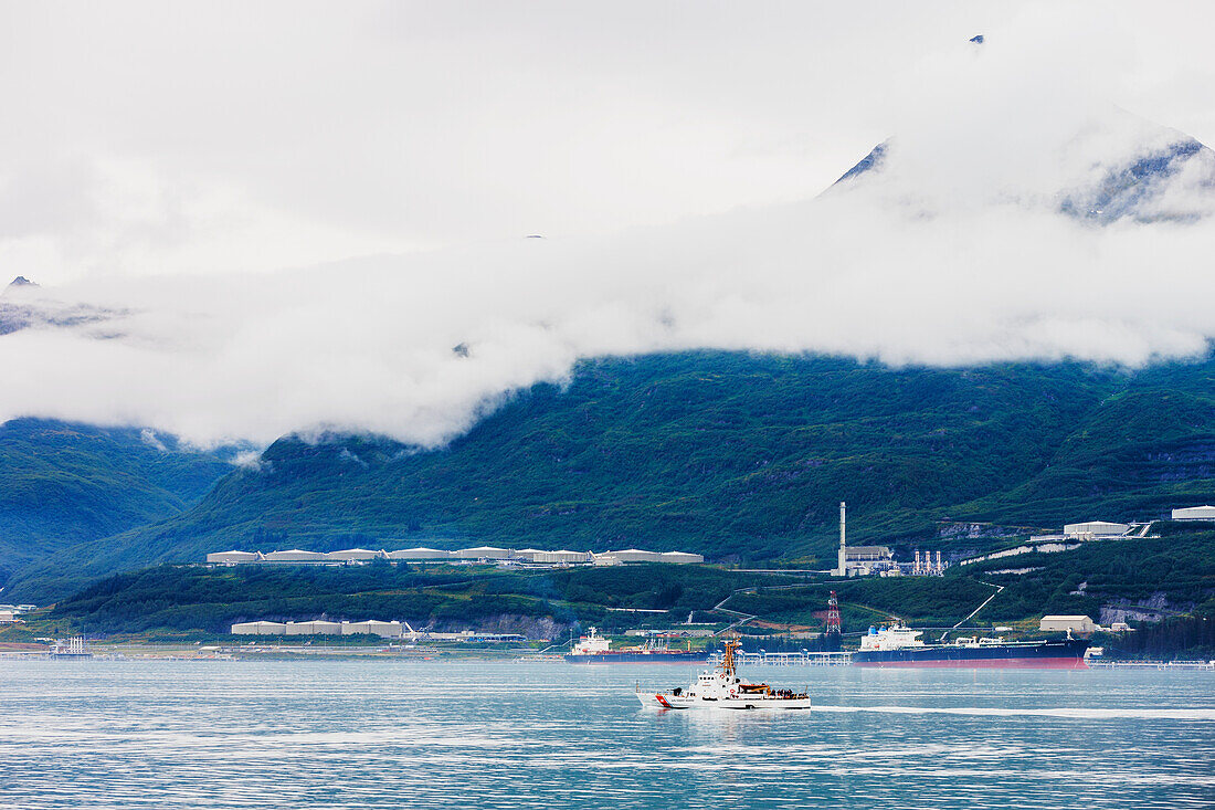 Coast Guard cutter returning to Valdez with misty clouds and mountains in the background, Valdez small boat harbor, Prince William Sound, Southcentral Alaska, USA.