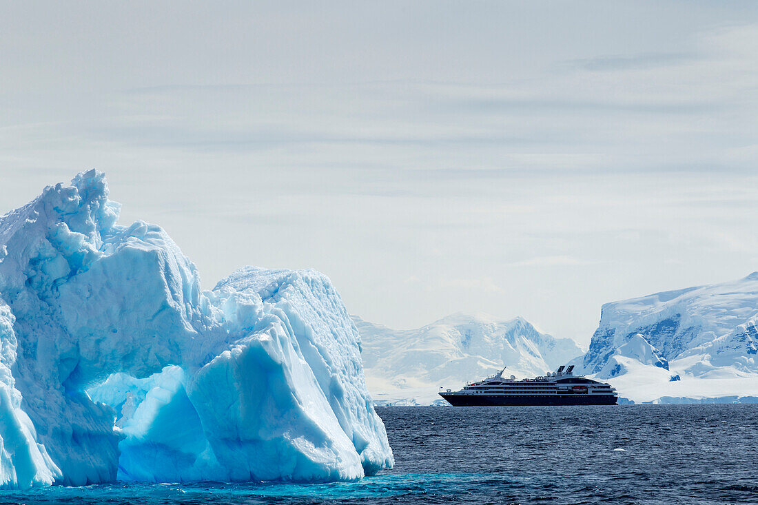 Antarctica, Cruise ship motoring past glacier-covered mountains on Anvers Island along Gerlache Strait