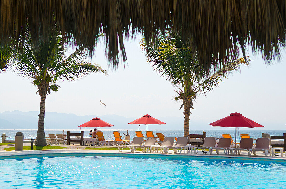 'Resort pool, umbrellas, palm trees and ocean view; Puerto Vallarta, Jalisco, Mexico'