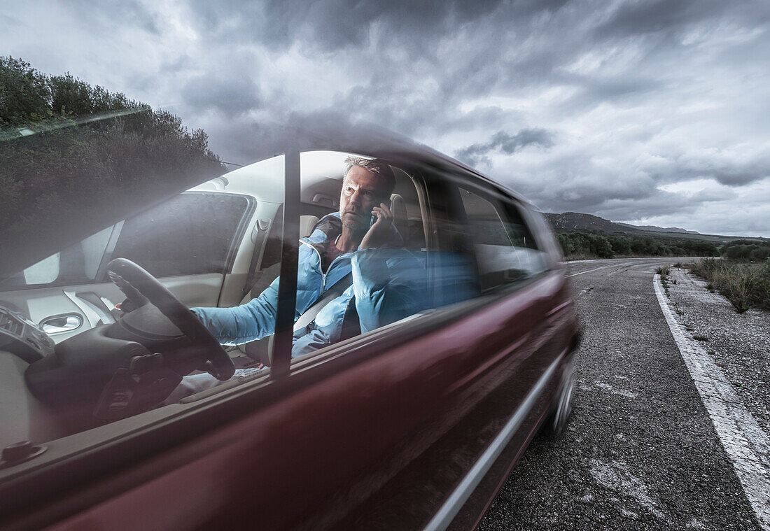 'A man talking on his phone while driving; Tarifa, Cadiz, Andalusia, Spain'