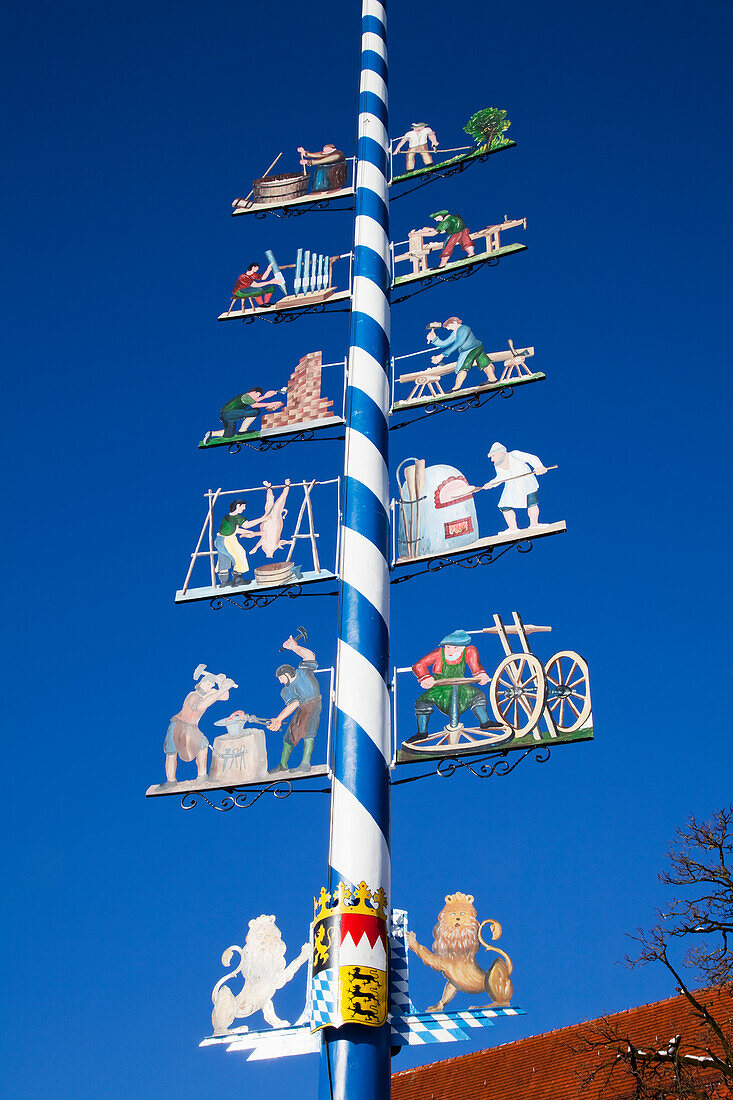 'Colourful images decorate a blue and white striped pole; Erling, Bavaria, Germany'