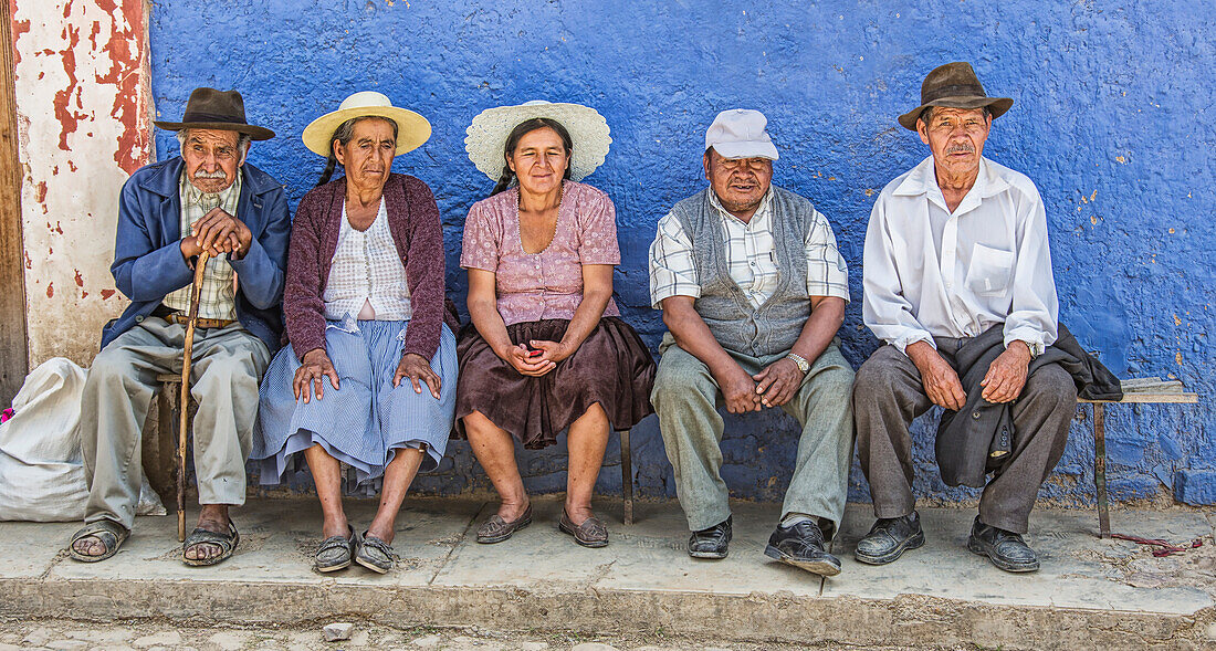 'A group of elderly Bolivian people sit on a bench watching a basketball game on a hot afternoon; Bolivia'