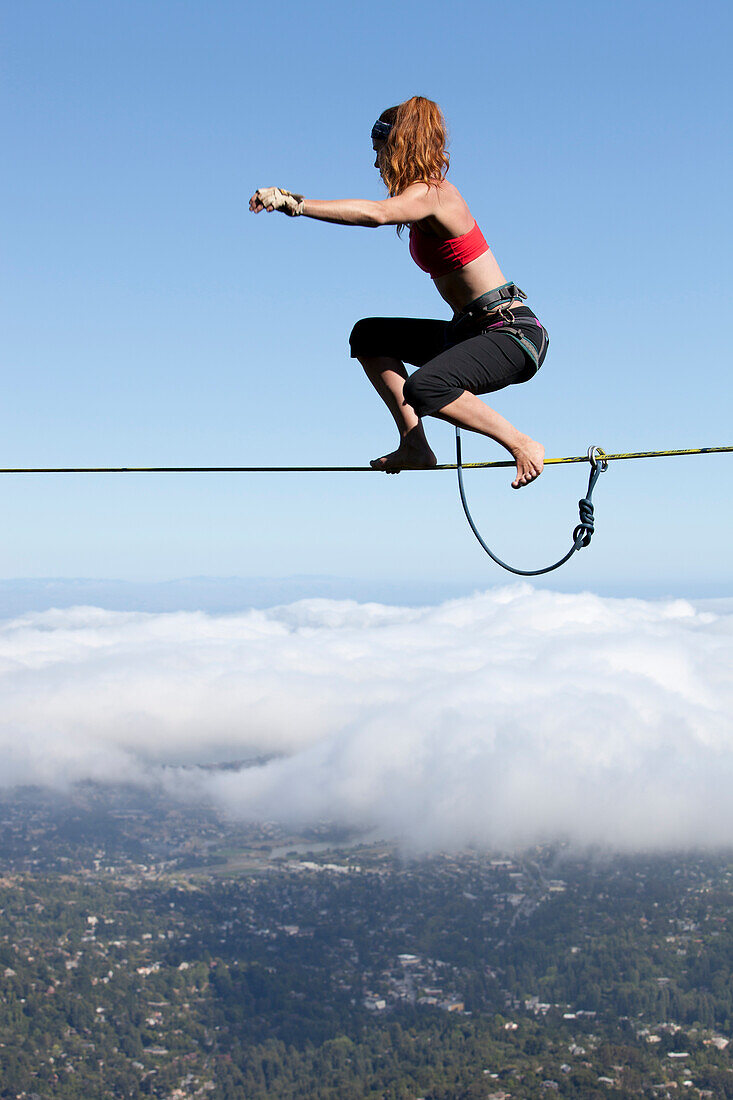 Professional highliner Hayley Ashburn stands up on a highline above the clouds atop Mount Tamalpais