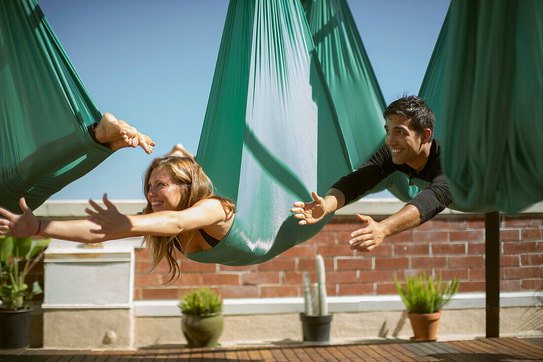 Ein schönes Mädchen und ein junger Mann machen Aerial Yoga in San Diego, Kalifornien.