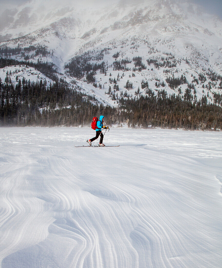 A woman skis on wind patterned snow at Two Medicine Lake, Glacier National Park, Montana.