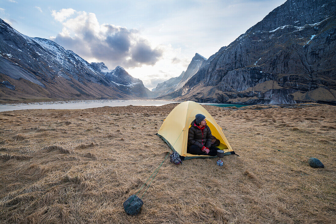 Female backpacker takes in view from tent while camping at Horseid beach, Moskenes??y, Lofoten Islands, Norway