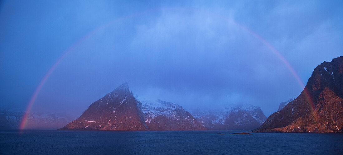 Rainbow forms over Olstind mountain peak and Fjord, Reine, Moskenes??y, Lofoten Islands, Norway