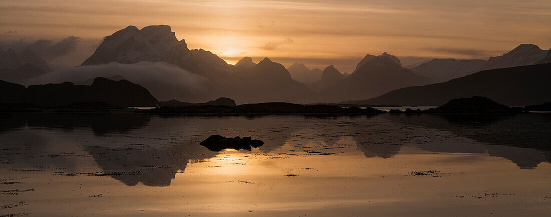 Mountains of Moskenes??y rise above sea at sunset, near Fredvang, Flakstad??y, Lofoten Islands, Norway