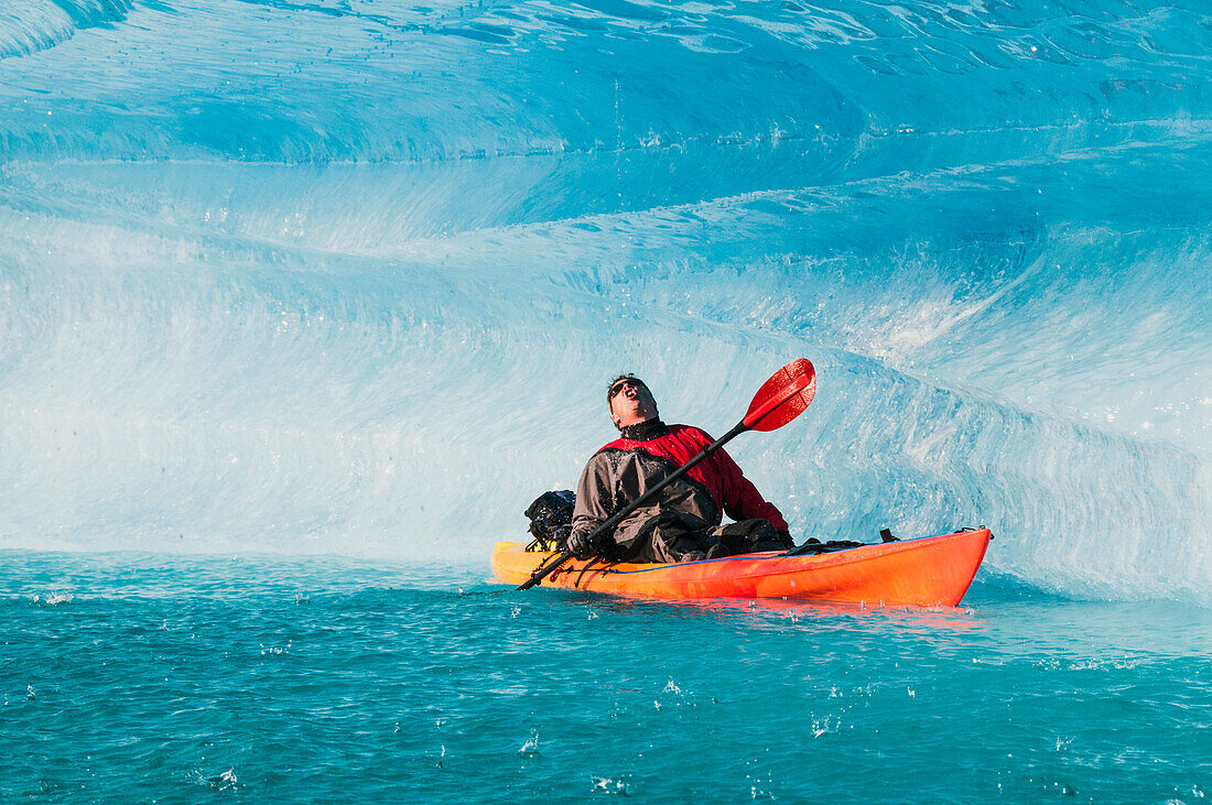 A man on kayak drinks water from a melting iceberg on Bear Lake in Kenai Fjords National Park, Alaska.