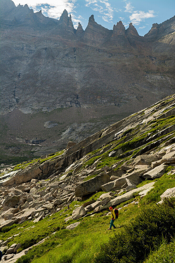 A young girl hiking down a grassy hillside in Glacier Gorge in the Rocky Mountain National Park, Estes Park, Colorado.