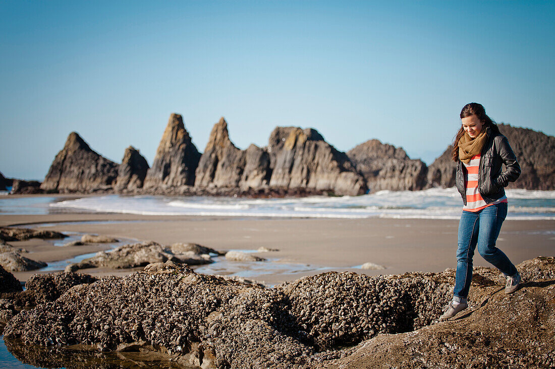 A young woman explores tide pools at Seal Rock Beach, Oregon.
