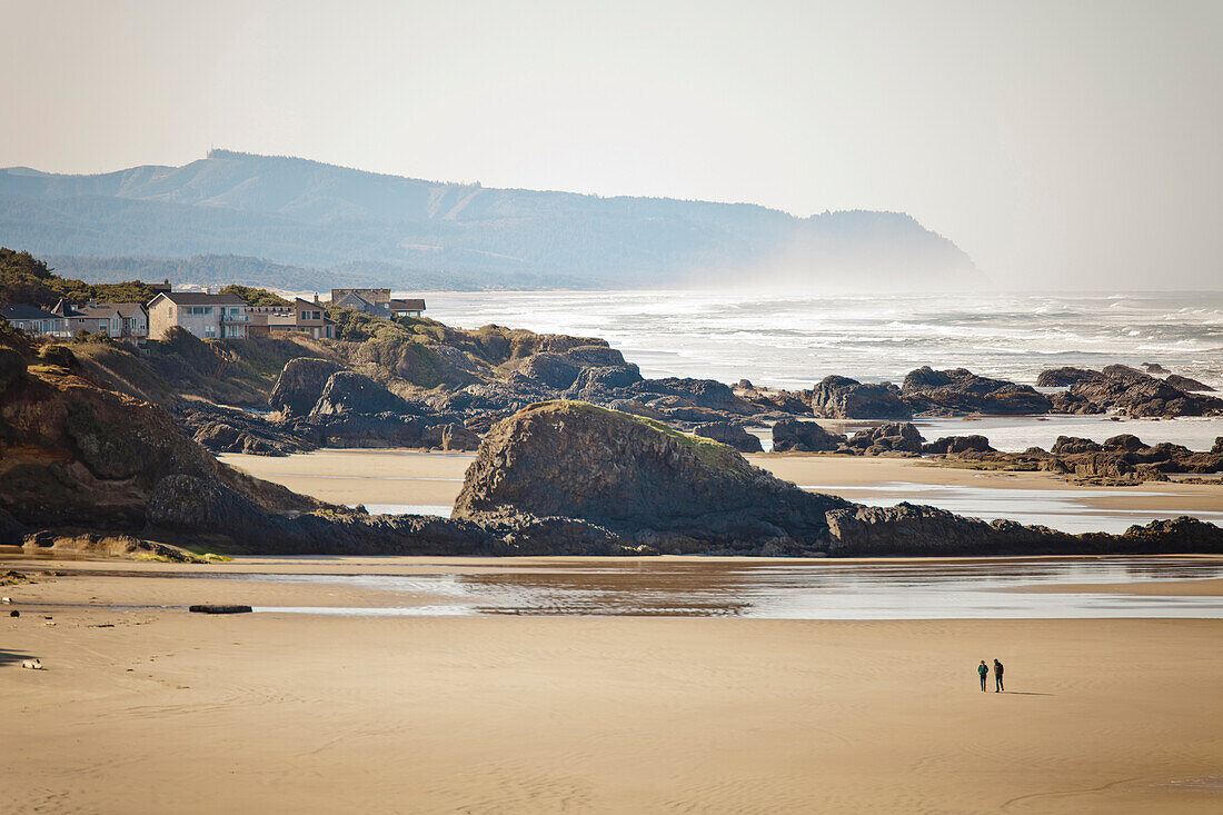 Two people walking on Seal Rock Beach, Oregon Coast.