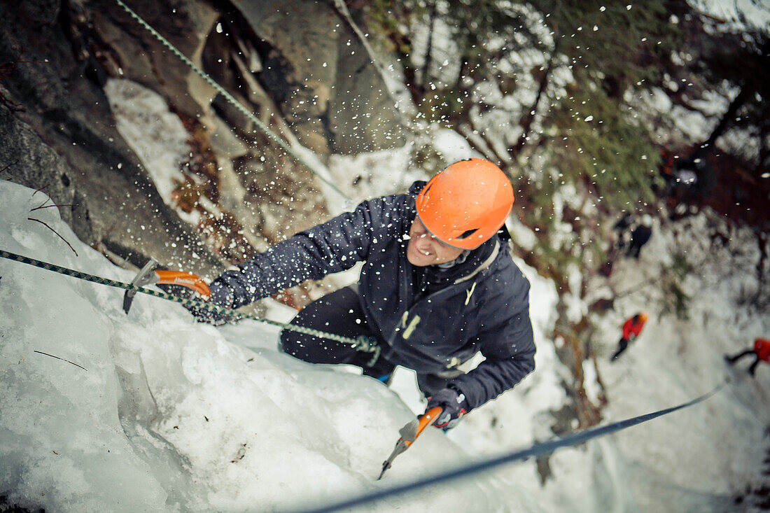 A male climber is sprayed with ice chunks while Ice climbing near Whistler, BC, Canada.