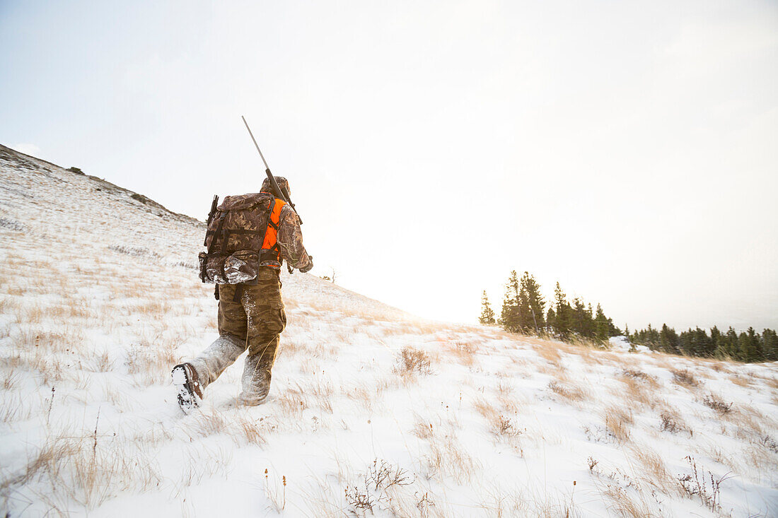 A male hunter at sunrise in the snow.