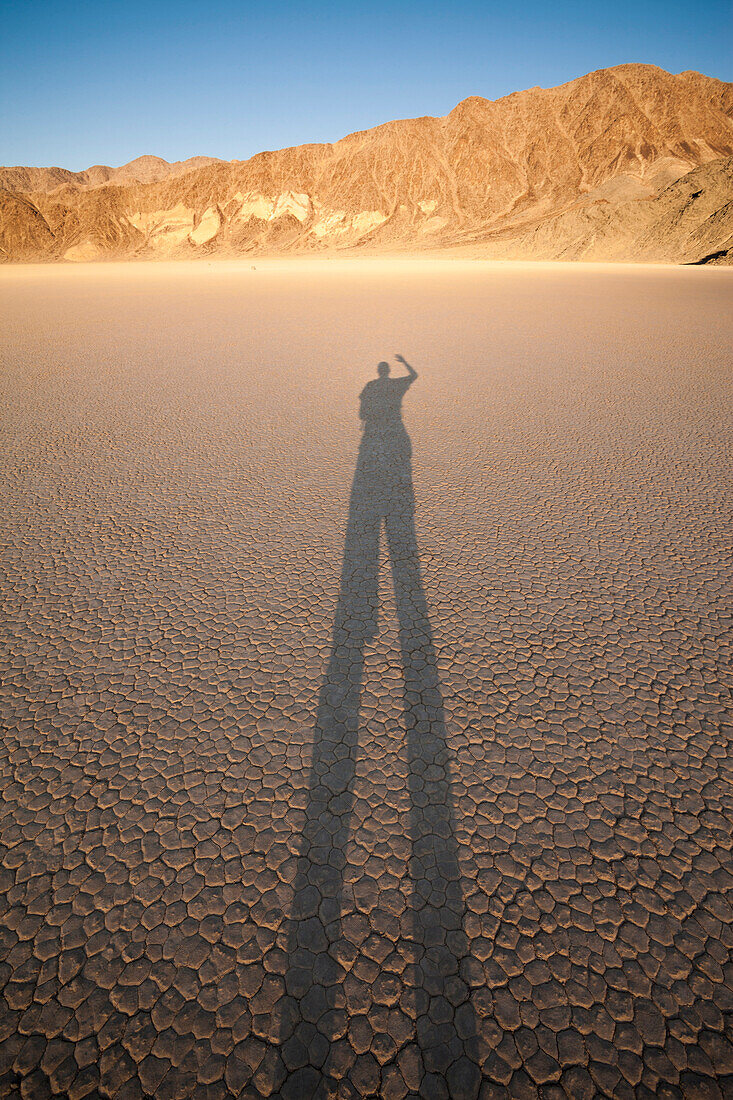 A person takes a photo of their shadow on the Racetrack Playa in California's Death Valley National Park.