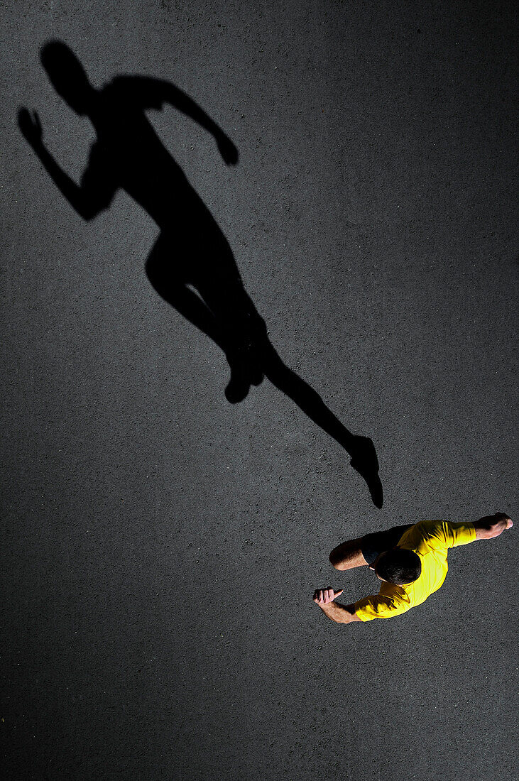 The young runner and his shadow on the asphalt in Barcelona, Spain.