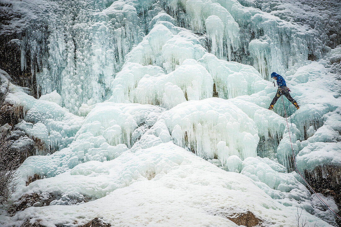 Man lead climbing an ice fall in the middle of a snow storm in Argenti?®re, Chamonix, France.