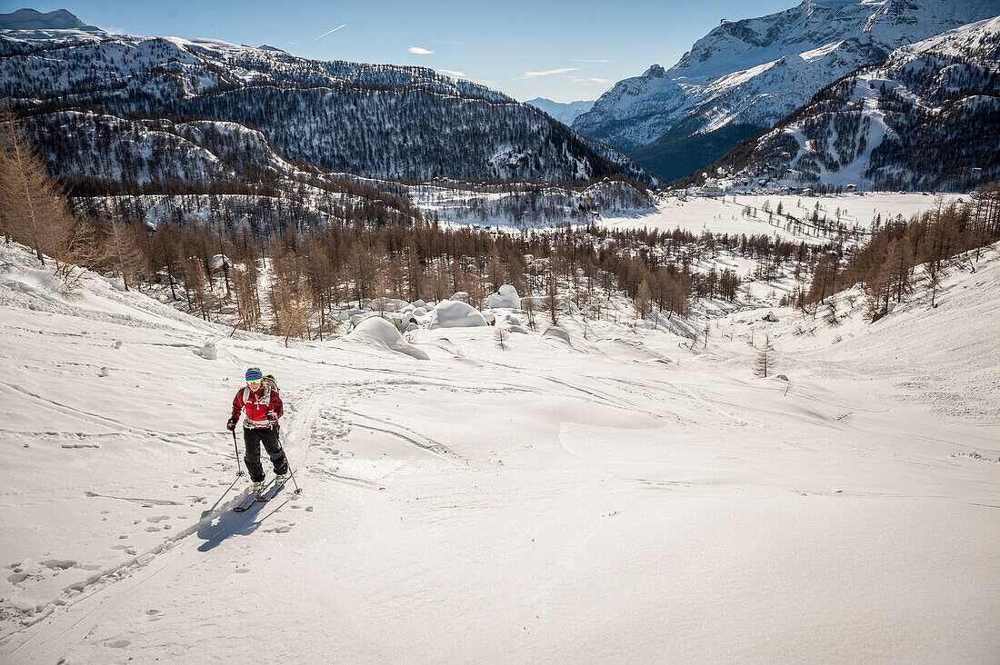 Girl with red jacket cross country skiing above Devero Valley. Baceno, Ossola, Italy.