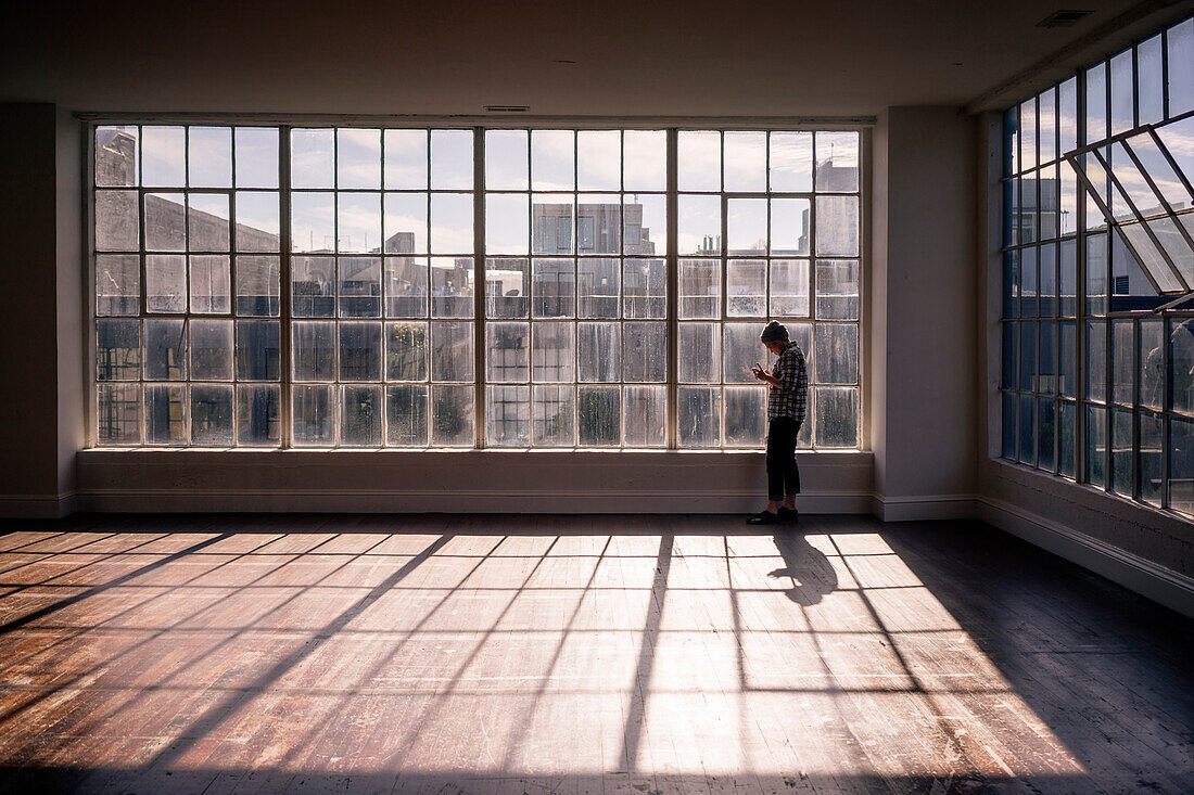 A woman standing in front of panel windows as the sun lights an open room