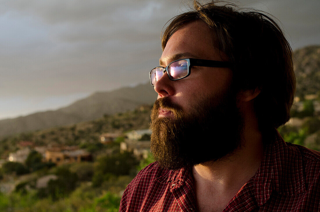 A man in his late twenties, takes in the view overlooking the city of Albuquerque, New Mexico.