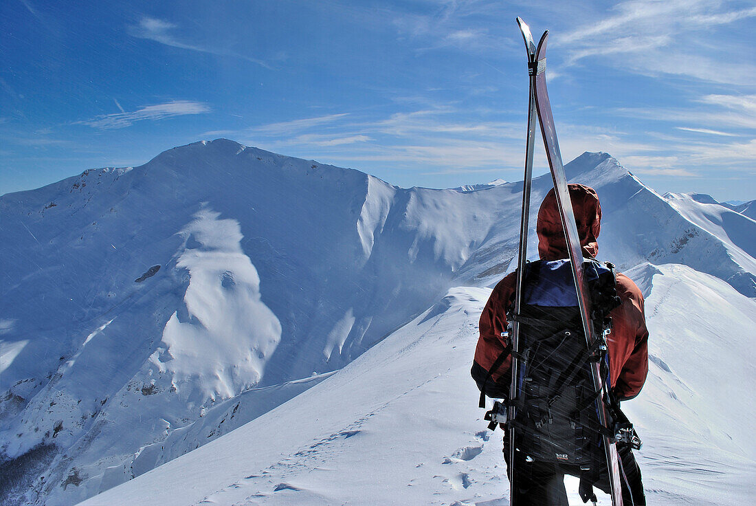 Male ski alpinist admiring mountain panorama.