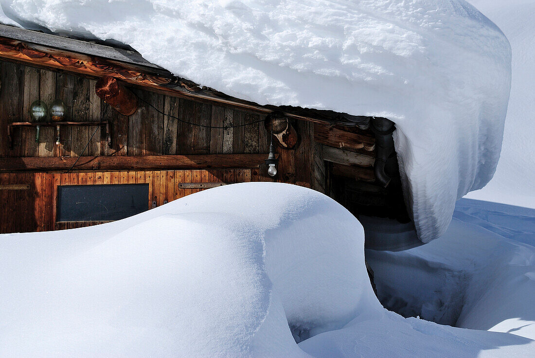 Old, rustic, wooden hous covered with snow.