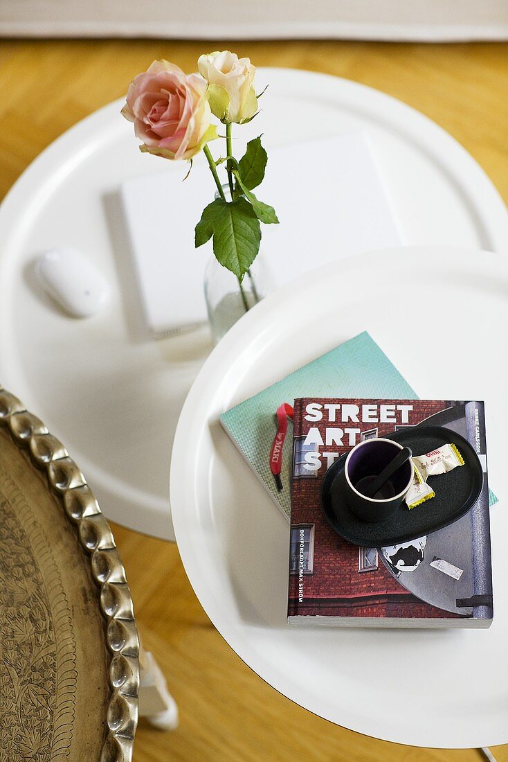 An espresso cup and a rose on a white side table