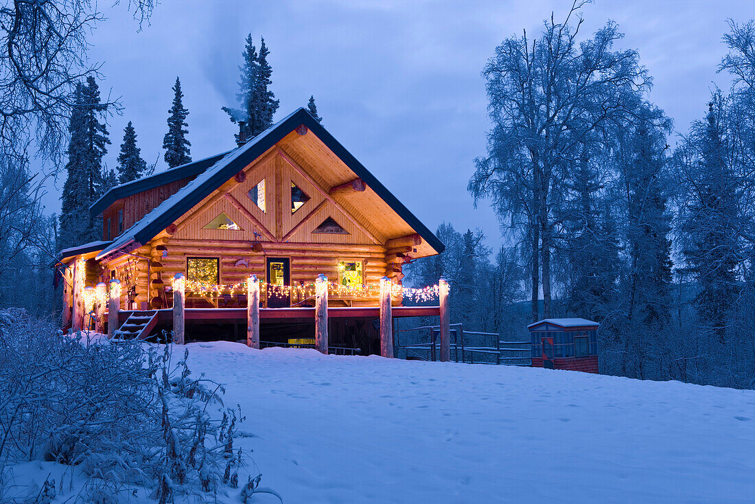 Log Cabin In The Woods Decorated With Christmas Lights At Twilight Near Fairbanks, Alaska During Winter