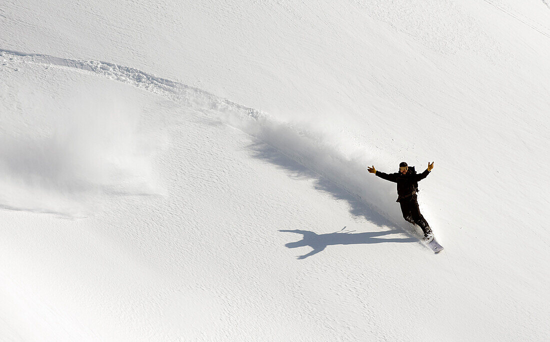 A Snowboarder Throws Up His Arms In Celebration While Snowboarding In Turnagain Pass Backcountry, Southcentral, Alaska