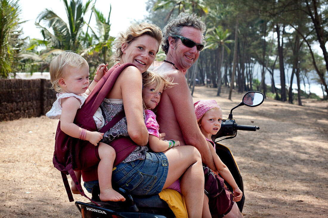 The Reynolds family on holiday in Goa transport the family Indian style 5-up on a moped, Turtle Beach, Goa, India.