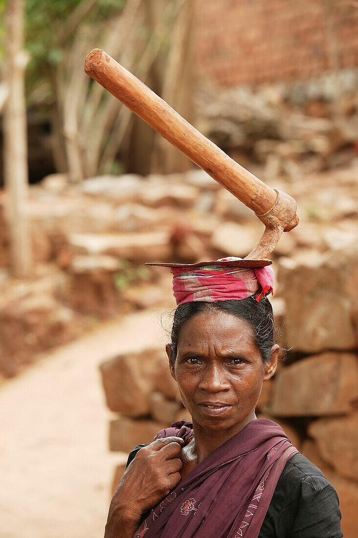 'A woman day labourer carries a digging tool on her head as she returns home; Kharigoda Village, Giajapati District, Orissa, India'