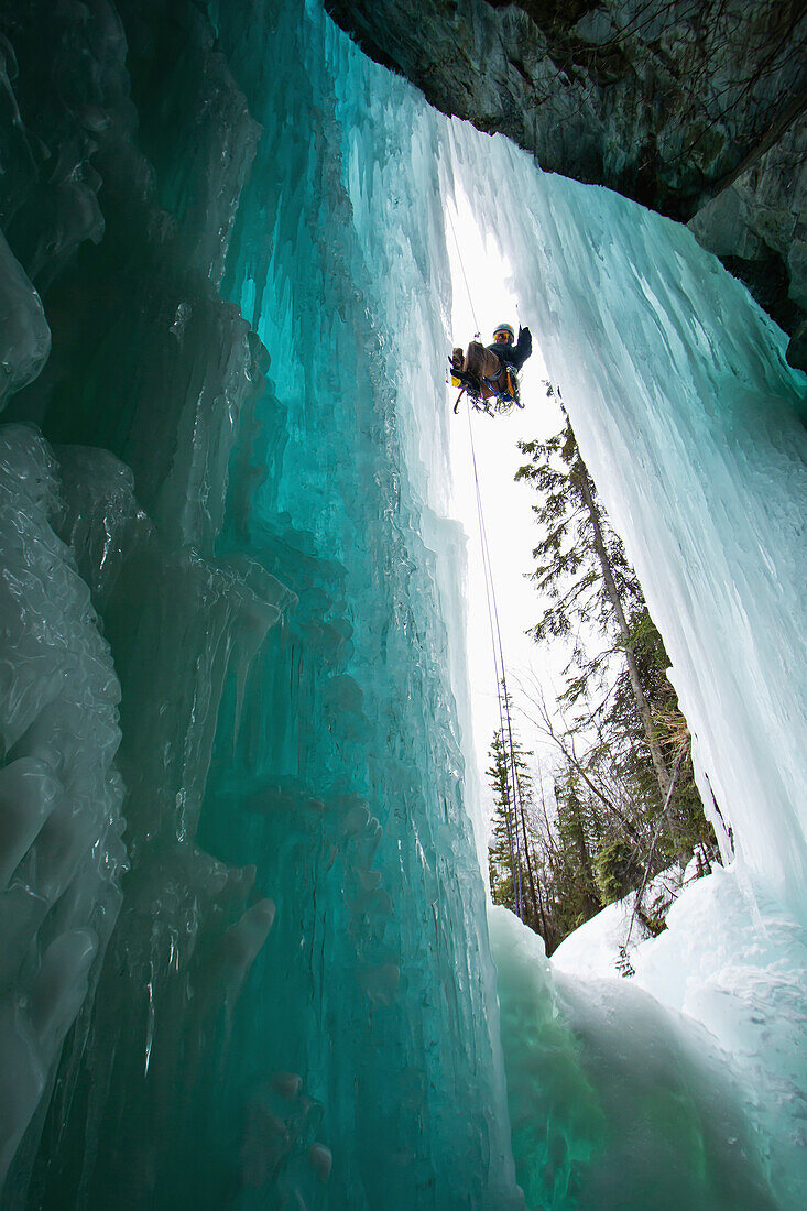 Ice climber rappelling down a frozen waterfall, Thompson Pass, Valdez, Alaska