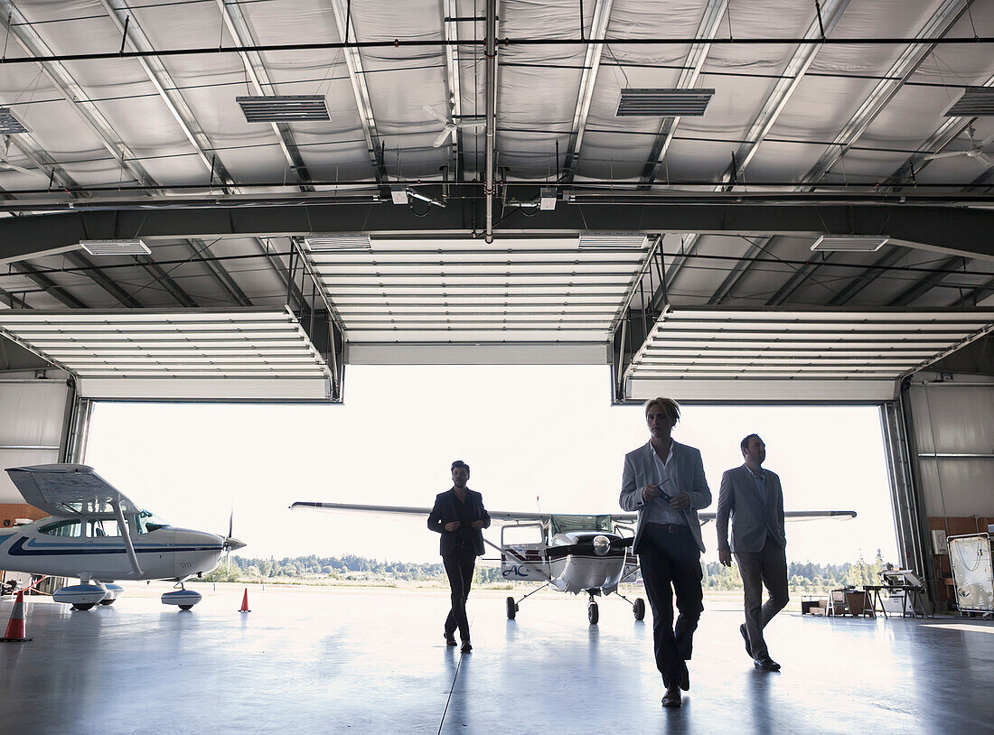 'Three businessmen entering airplane hangar; Langley, British Columbia, Canada'