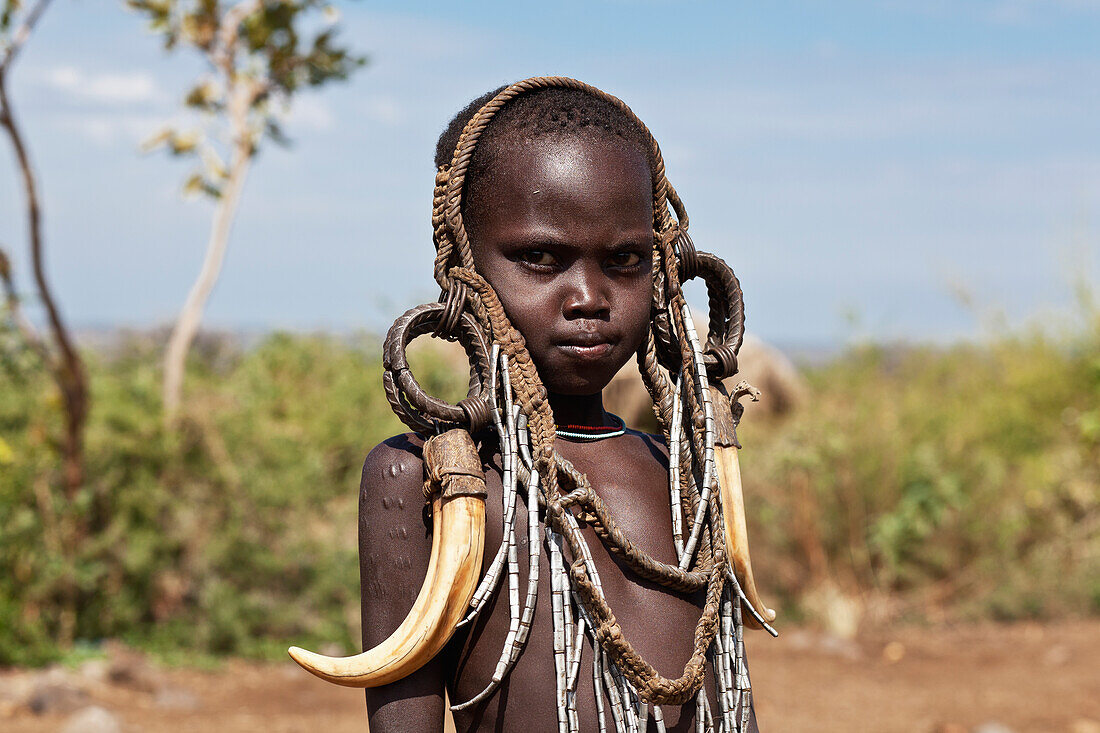 'Portrait of a child decorated with tribal accessories; Omo Valley, Ethiopia'