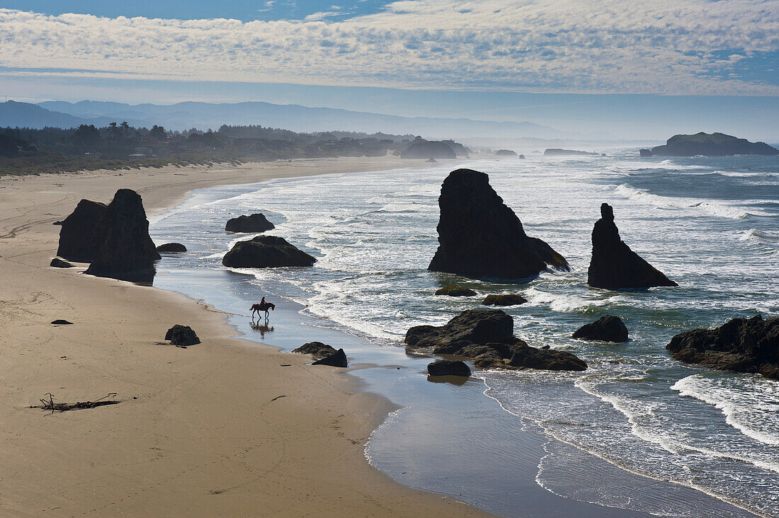 'A woman takes a tranquil horseback ride on a solitary Pacific Ocean beach; Bandon, Oregon, United States of America'